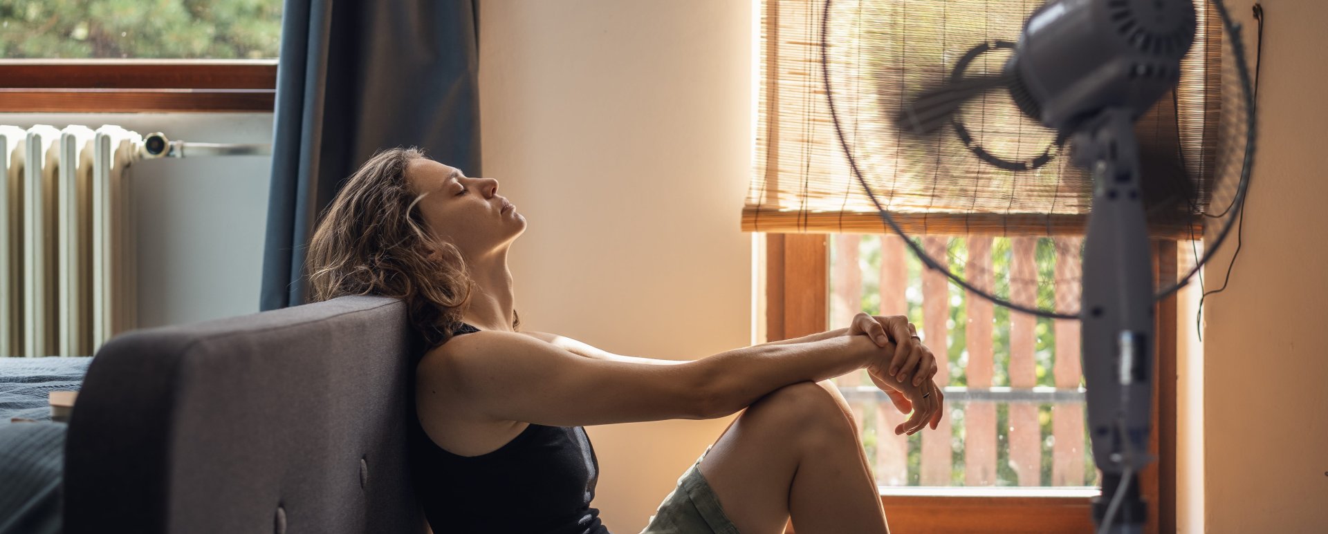 Frau sitzt vor Ventilator