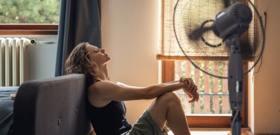 Frau sitzt vor Ventilator