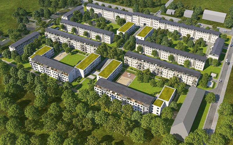 Große Mehrfamilienhaussiedlung von oben, darum Wald und Wiesen