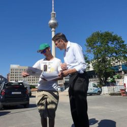 Zwei Personen schauen in Unterlagen dahinter Fernsehturm