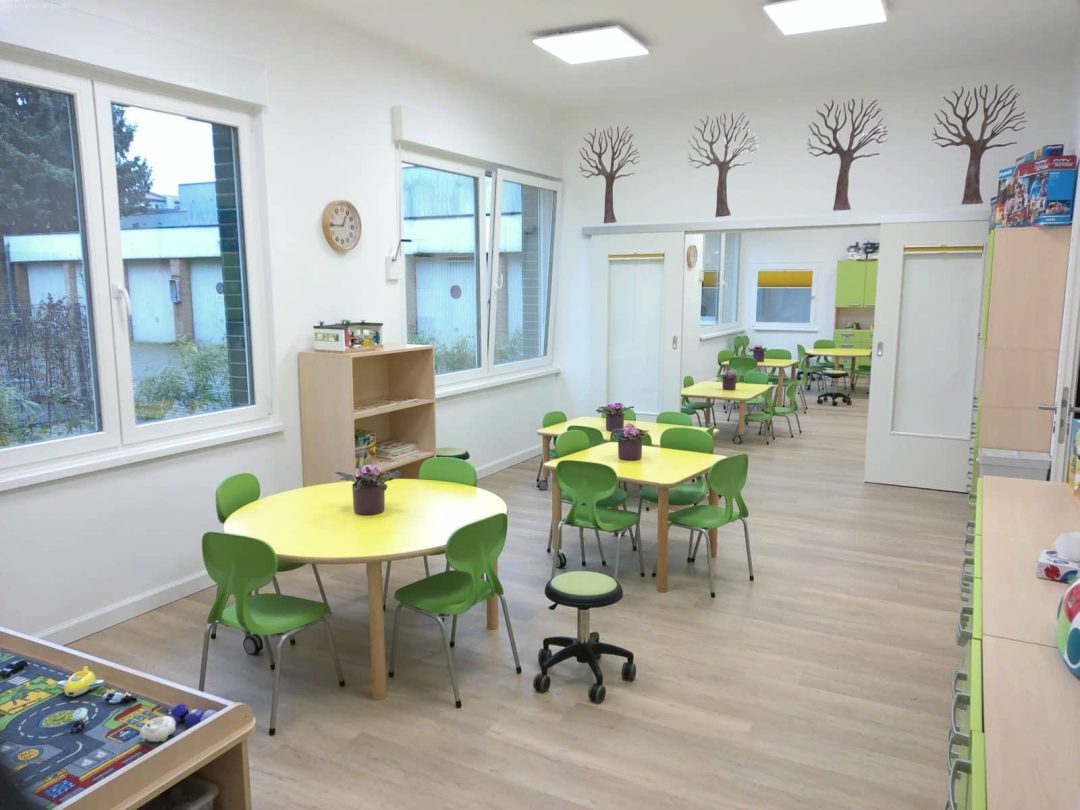 Raum mit vielen grünen Tischen und Stühlen