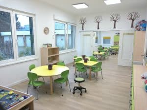 Raum mit vielen grünen Tischen und Stühlen