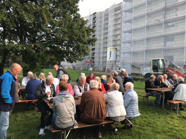 Menschen sitzen an Bierzelttischen auf Rasen