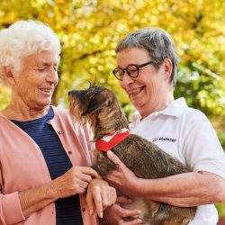 Zwei ältere Frauen mit Dackel auf dem Arm