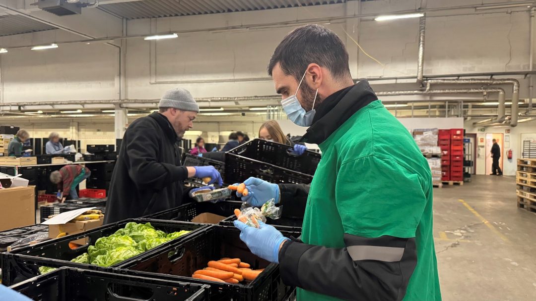 Mann mit Gesichtsmaske und Handschuhen sortiert Gemüse