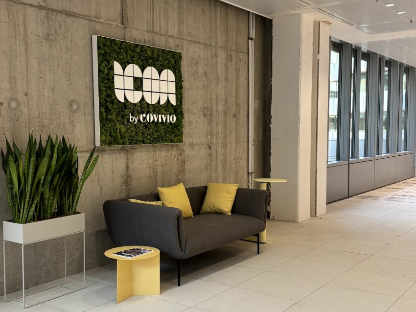 Offener Raum mit Möbeln einer Mooswand mit Logo und weiterer Pflanze