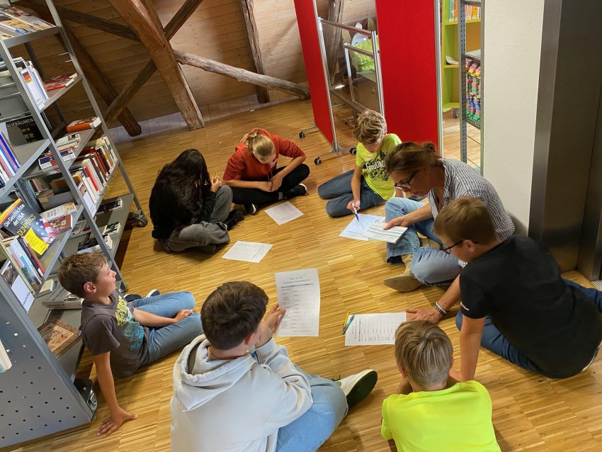Gruppe von Kindern sitzt im Kreis auf dem Boden
