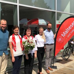 Gruppe von fünf Personen, eine mit Blumenstrauß