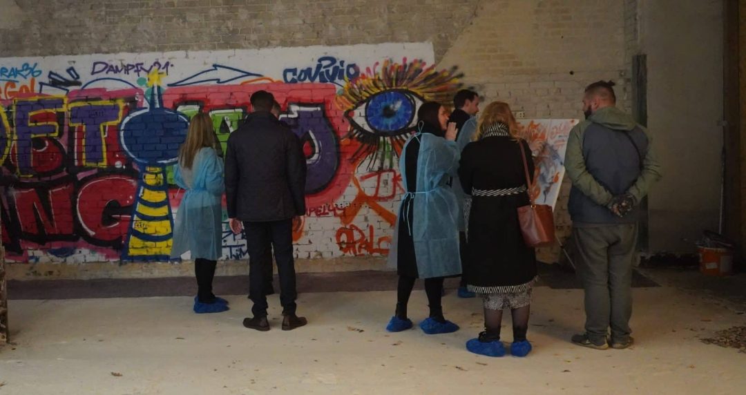 Personen betrachten Graffiti an Mauer