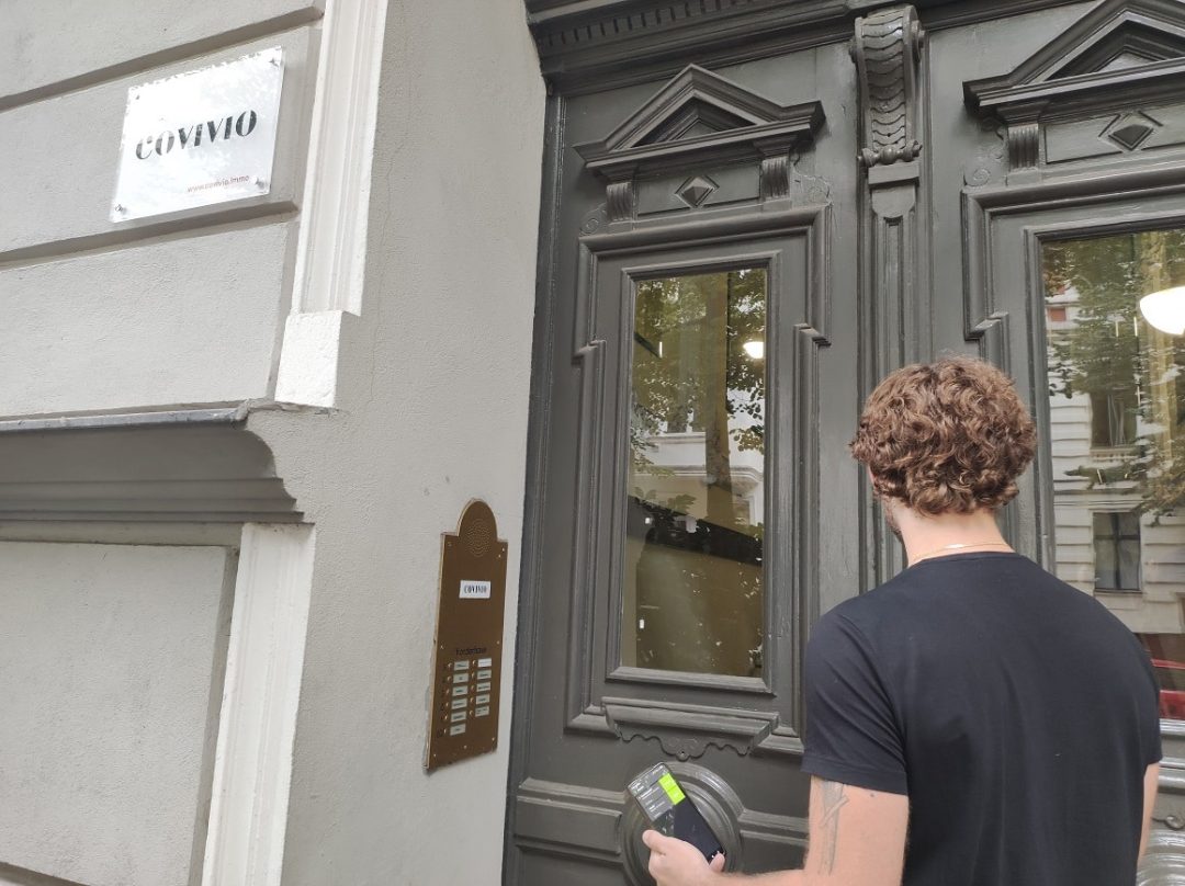 Mann mit Smartphone vor Hauseingang