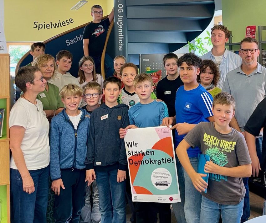 Gruppe von Jugendlichen. Eine Person hält ein Plakat mit der Aufschrift