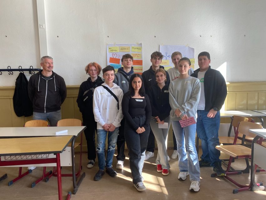 Gruppe vor Jugendlichen steht vor einer Wand